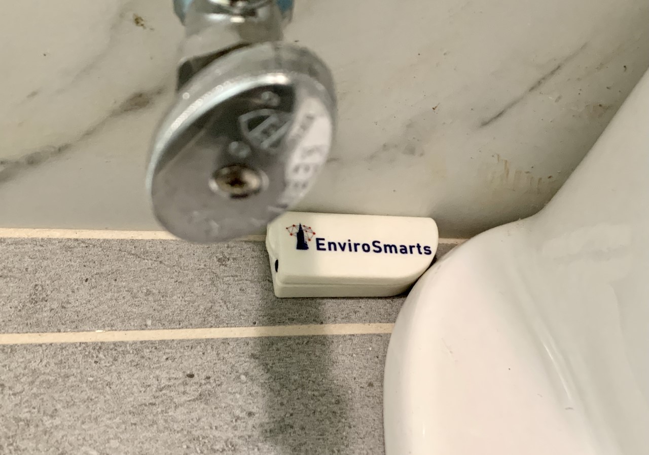 EnviroSmarts sensor installed behind toilet — real-world water leak detection